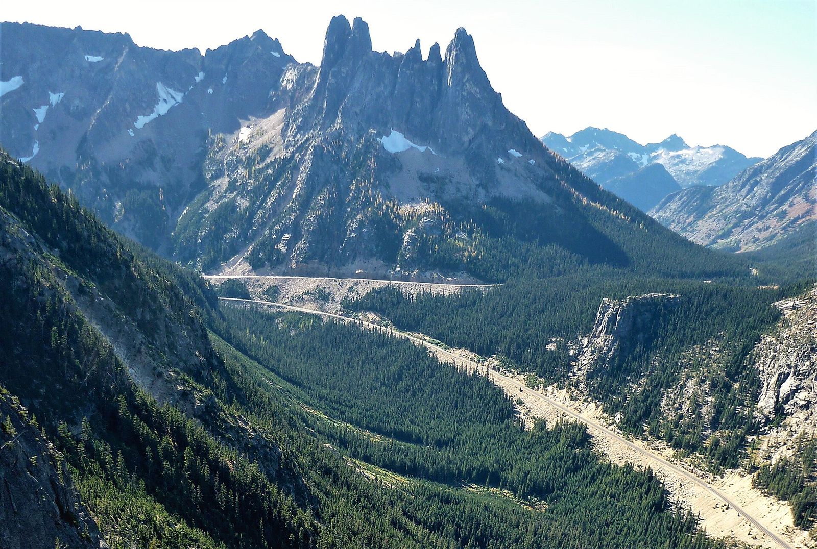The North Cascades Highway winding through a forested valley below the jagged Liberty Bell group of peaks