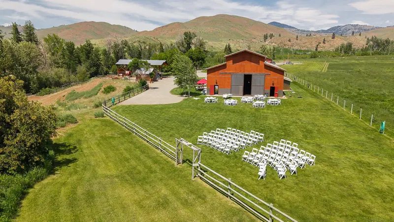Aerial view of the red event barn, ceremony chairs on the lawn and rail fences